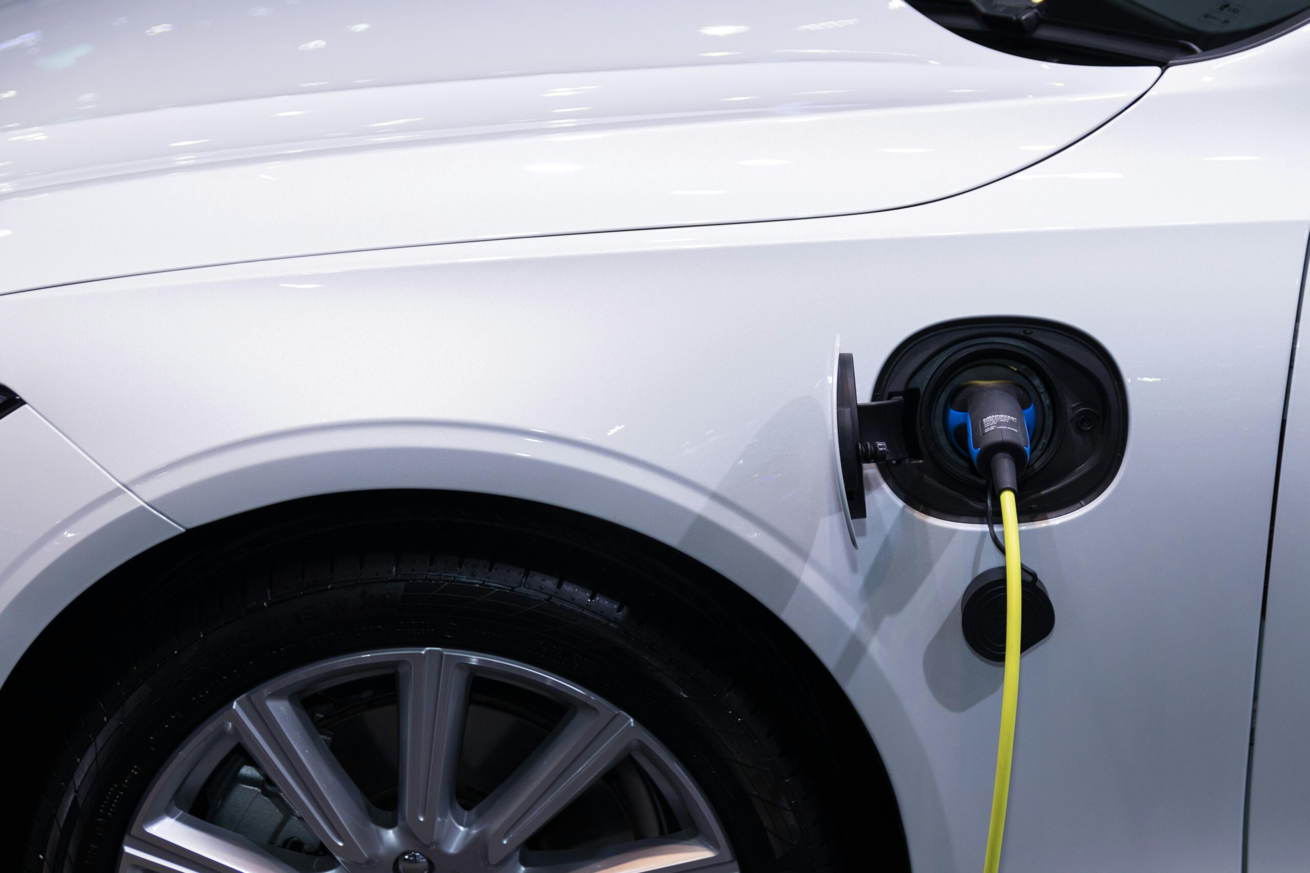 2026 : TESLA VS BYD A white electric car is plugged in for charging, close-up view of the charging port.